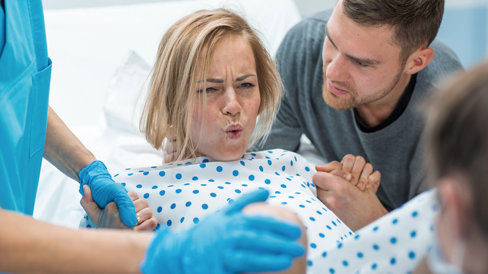 Femme tenant la main de son mari et de l'infirmière pendant l'accouchement.