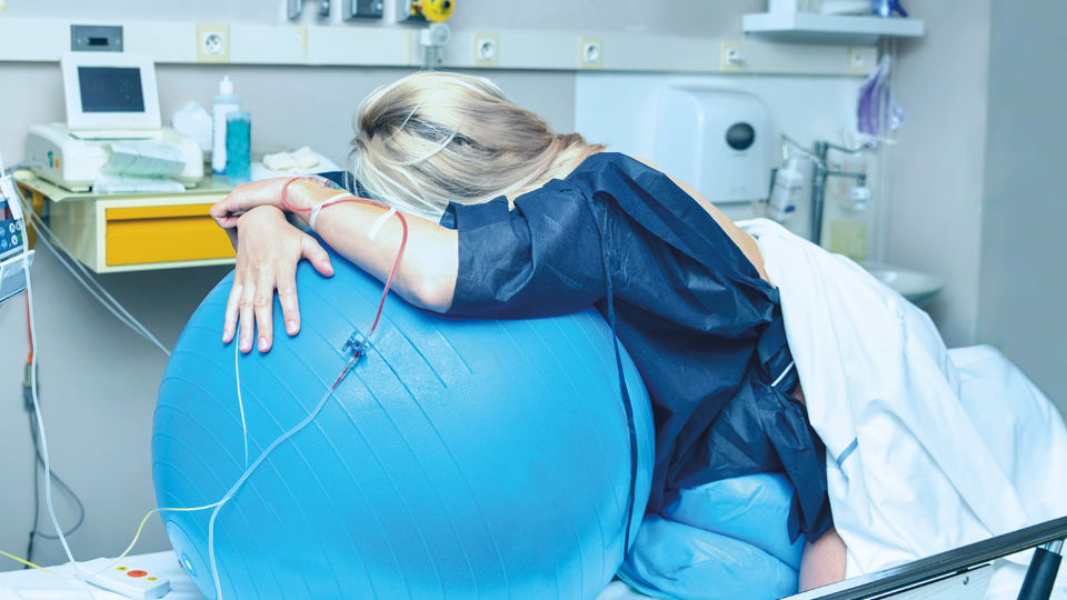 Une femme enceinte pendant l'accouchement, allongée sur un gros ballon.